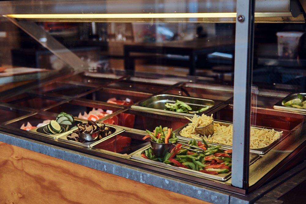 Close-up image of metal containers with different vegetables for fast food take away in the cafe.
